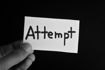 Hand holding a paper card with the word ATTEMPT