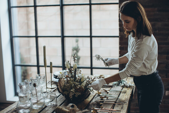 Table setting for the holiday. Table decor with soft candles and natural elements that create an attractive atmosphere. The process of decorating a dining table in a rustic style.