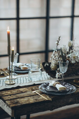 Table setting for the holiday. Table decor with soft candles and natural elements that create an attractive atmosphere. The process of decorating a dining table in a rustic style.