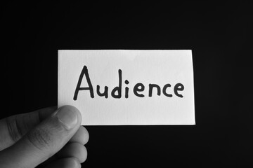 Hand holding a paper card with the word AUDIENCE