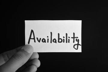 Hand holding a paper card with the word AVAILABILITY