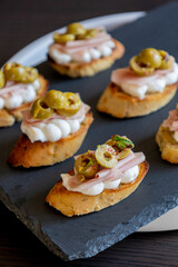 beautiful and delicate party appetizer featuring slices of cheese, mortadella, salami, and green olives