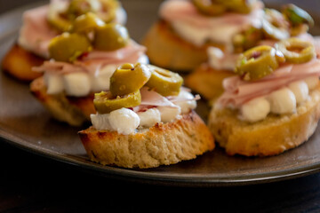 beautiful and delicate party appetizer featuring slices of cheese, mortadella, salami, and green olives