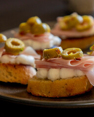 beautiful and delicate party appetizer featuring slices of cheese, mortadella, salami, and green olives