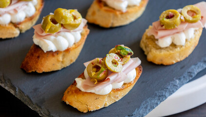 beautiful and delicate party appetizer featuring slices of cheese, mortadella, salami, and green olives