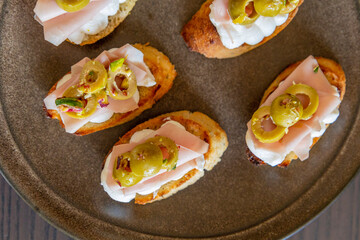 beautiful and delicate party appetizer featuring slices of cheese, mortadella, salami, and green olives