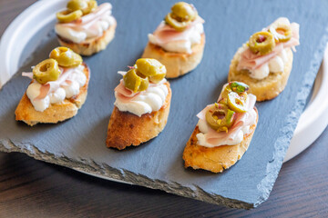 beautiful and delicate party appetizer featuring slices of cheese, mortadella, salami, and green olives