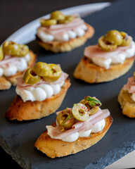 beautiful and delicate party appetizer featuring slices of cheese, mortadella, salami, and green olives