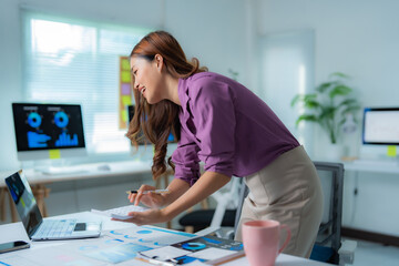 Asian businesswomen cheering and jumping with arms raised in a bright modern office, celebrating...