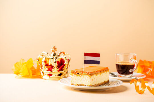 Stack of orange tompouce and donuts glazed donuts with red, white and blue sprinkles topped with a small Dutch flag on wooden board. National holiday Koningsdag on 27 April in the Netherlands