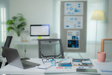Marketing strategy documents and charts are spread out on a desk in a modern office, suggesting a focused effort in developing effective business plans and analyzing market trends