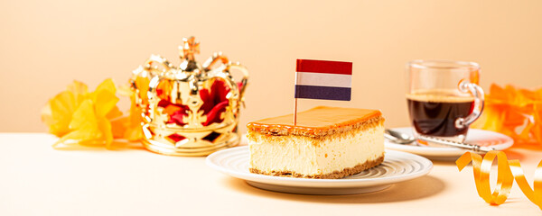 Banner with orange tompouce and topped with a small Dutch flag on wooden board. National holiday Koningsdag on 27 April in the Netherlands. Holland culture concept with copy space