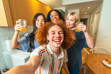 Happy friends taking a selfie while drinking juice in the kitchen