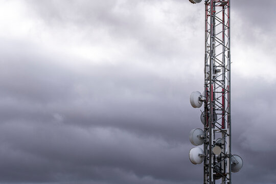 Telecom tower with antennas against cloudy sky in Zaragoza. Communication infrastructure, vertical structure and signal technology in industrial environment.