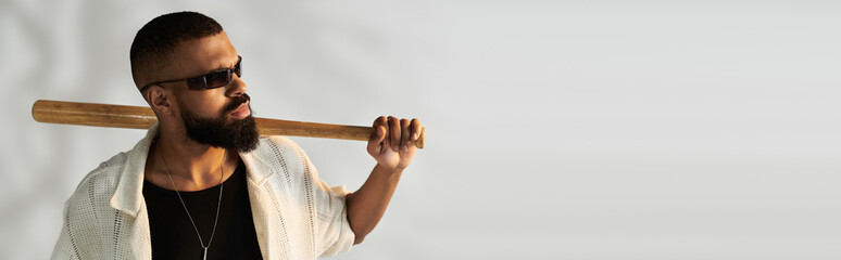 Stylish young man with a baseball bat showcasing a confident fashion sense and modern attitude