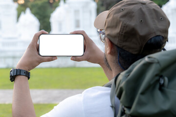 A male tourist is using his phone camera to take photos during his trip