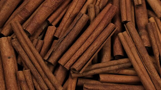 Heap of cinnamon sticks close up, rotation. Food cooking video concept