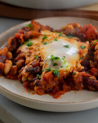  eggs and beans dinner served in a white dish close-up