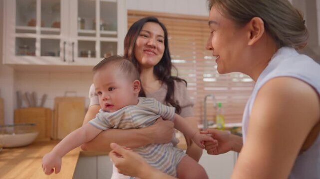 Asian lesbian couple lovingly caring for and raising their baby boy at home. 
