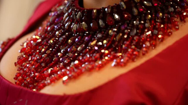 Fashion detail: hands with beaded bracelets adjusting a red dress.