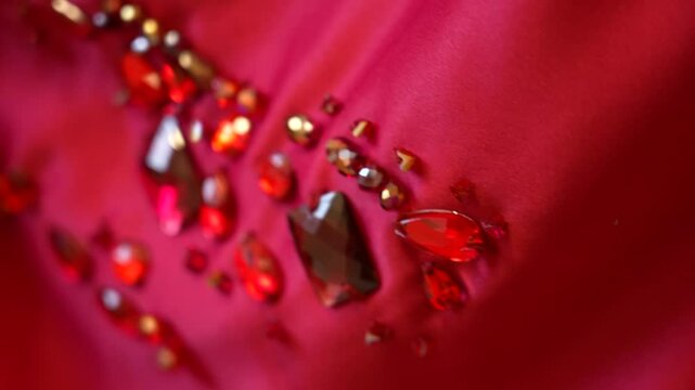 Fashion detail: hands with beaded bracelets adjusting a red dress.
