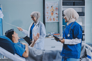Obraz premium A young man lies on a bed in a hospital ward talking with her young Indian doctor. Doctor checking patient's health doctor treating patient, hospital admission of patient
