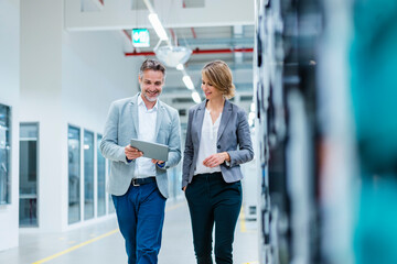 Business professionals discussing in a production hall with a tablet