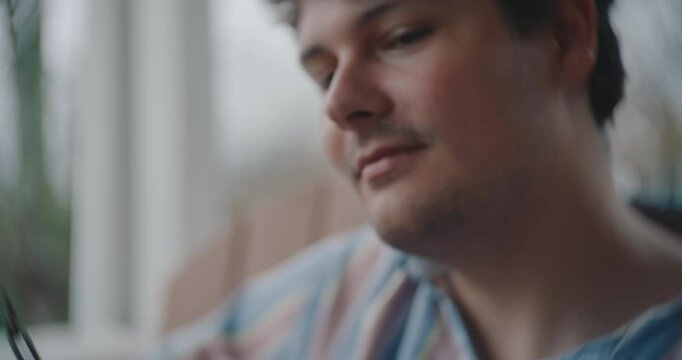 Young male musician sitting on a porch, playing guitar and writing a song