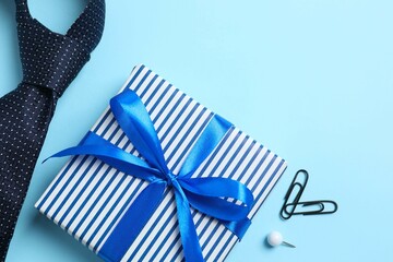 Top view photo of giftbox with silk ribbon bow and blue tie, on color blue background