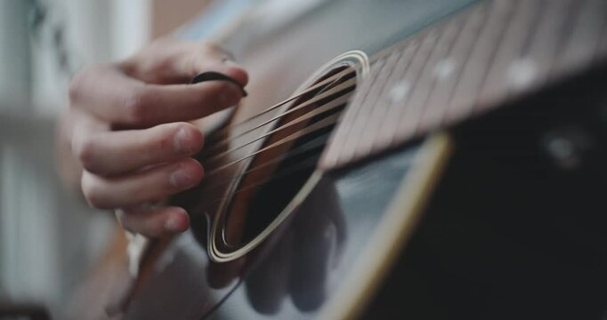 Close up of hands strumming and playing the acoustic guitar 