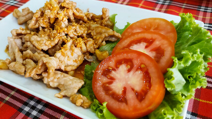  Delicious stir-fried pork with garlic and pepper, garnished with fresh tomato and lettuce, served on a white plate