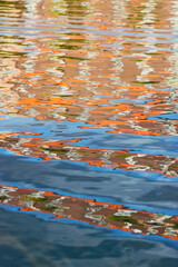 Colorful reflection on the water surface. Seaside in Helsinki, Finland. Play of yellow and orange colors in gently rippling water. The colors form an abstract pattern.