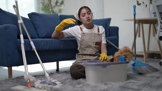 A woman is cleaning a room with a dog. She is wearing a yellow apron and gloves