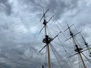 View of the ship's masts, platform and ropes, showing traditional marine details against a stormy sky. Photograph of the rigging of a vintage large sailboat. Marine rope ladder at ship.