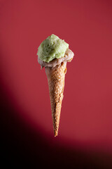 Artisan pistachio and almond gelato cone on red background minimal style