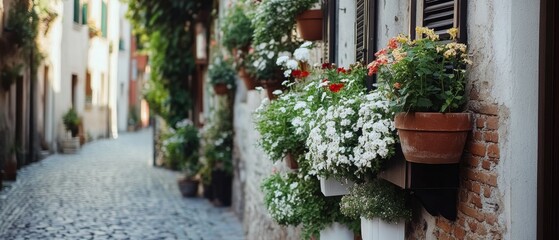Fototapeta premium Cobblestone street lined with rustic brick buildings and vibrant flower pots, evoking a serene, quaint European village charm.