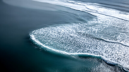 Aerial view of turquoise ocean waves forming abstract patterns with white foam, creating serene and dynamic seascape. contrast between deep blue water and frothy waves is captivating