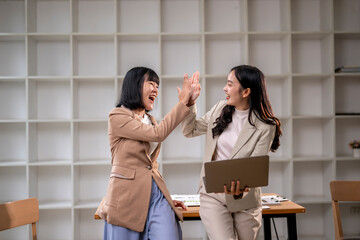 Two women are high fiving each other in a business setting