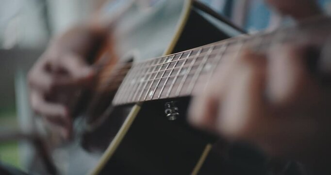 Close up of hands strumming and playing the acoustic guitar 