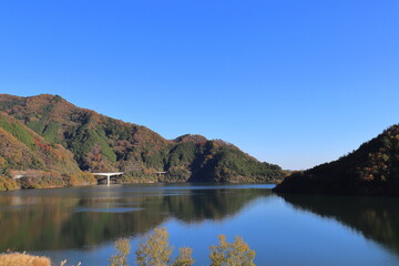 紅葉した山と奥津湖と青空