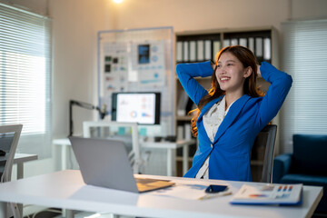 A woman is sitting at a desk with a laptop and smiling