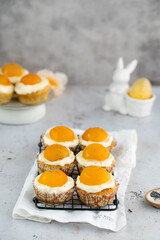 Lemon cupcakes with cream cheese, apricot and poppy seed. Cupcake in form of Fried Egg on a stone background. Easter eggs. Easter holiday and festive food.
