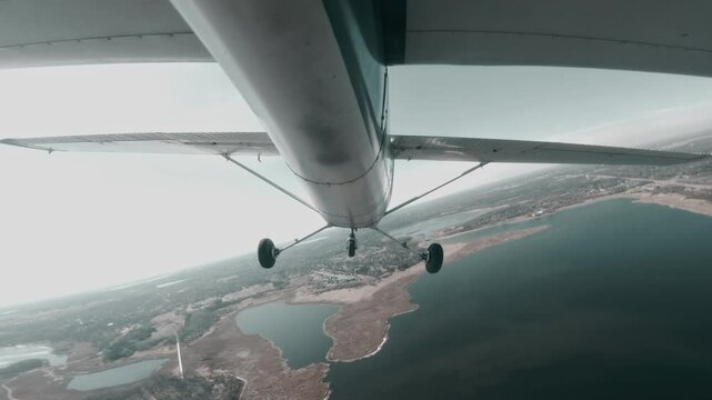 Light aircraft Cessna 150 turning over lake near suburban residential area.