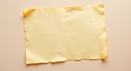 Paper surface background.  a slightly crumpled yellow paper with torn edges on a light beige surface in a studio shot