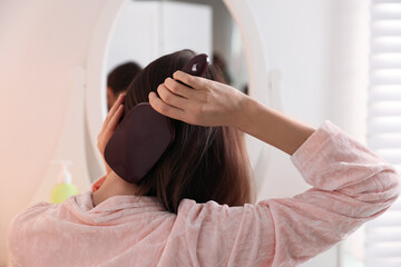 Naklejka premium Woman brushing her beautiful hair at home