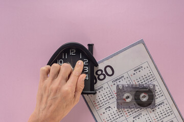 Male hand with old watch, calendar and audio tape cassette remembering music hits of 80s Vintage...