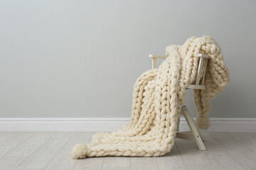 Knitted merino wool plaid on chair in room. Space for text