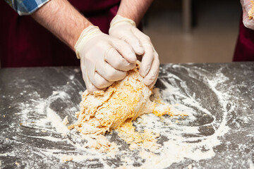 Hands kneading fresh pasta dough on counter.