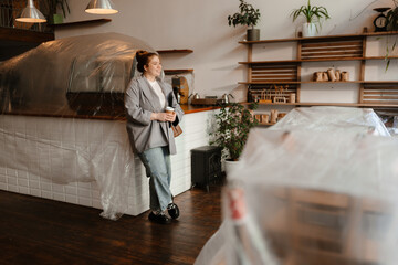 The woman smiles as she looks at the room she has arranged for her own caf?, already anticipating...