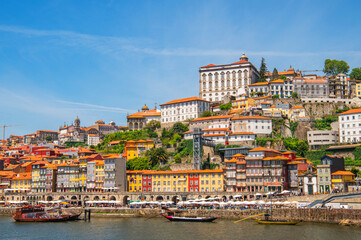 Fototapeta premium Cityscape of Porto (Oporto) over Douro River during a sunny day, Portugal. View of downtown Ribeira and embankment of Porto. Promenade view with colorful houses.